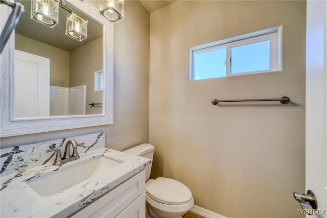 bathroom featuring vanity, toilet, and baseboards