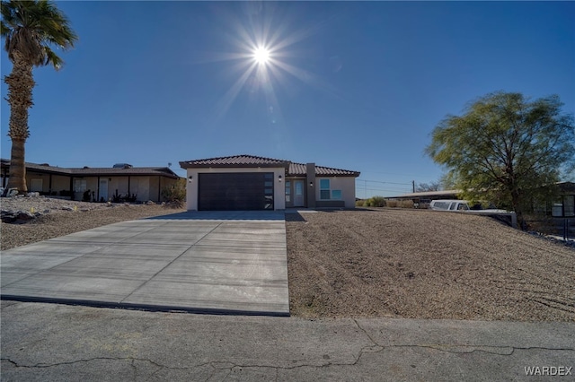 mediterranean / spanish-style home featuring concrete driveway, an attached garage, a tiled roof, and stucco siding