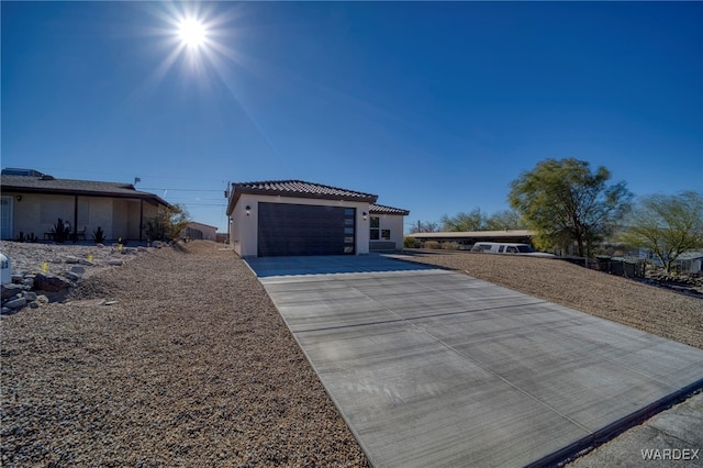 view of front of home with driveway, an attached garage, a tiled roof, and stucco siding