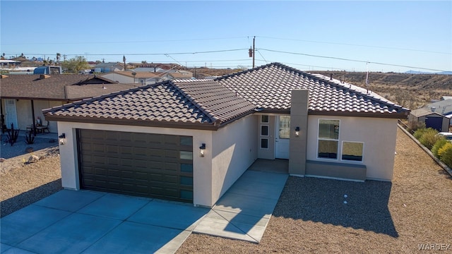 mediterranean / spanish house with concrete driveway, an attached garage, a tiled roof, and stucco siding