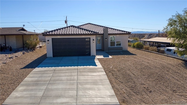 view of front of house with driveway, a tiled roof, an attached garage, and stucco siding