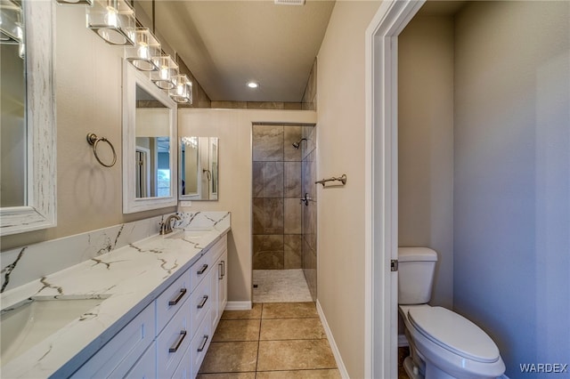 bathroom with a sink, tile patterned flooring, a tile shower, and toilet