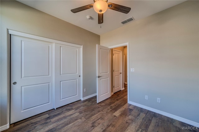 unfurnished bedroom featuring dark wood-style floors, baseboards, visible vents, and a closet