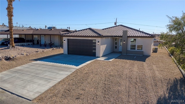 ranch-style house featuring an attached garage, a tiled roof, concrete driveway, and stucco siding