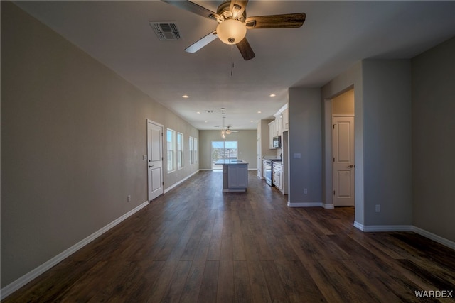 unfurnished living room with baseboards, visible vents, dark wood-style flooring, and recessed lighting