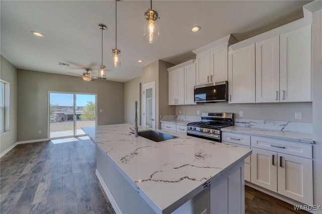 kitchen featuring white cabinets, an island with sink, decorative light fixtures, stainless steel appliances, and a sink