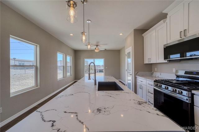 kitchen with baseboards, stainless steel appliances, white cabinets, and pendant lighting