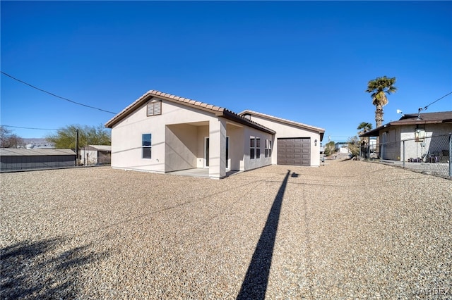 view of front of house featuring an attached garage, a tiled roof, fence, and stucco siding