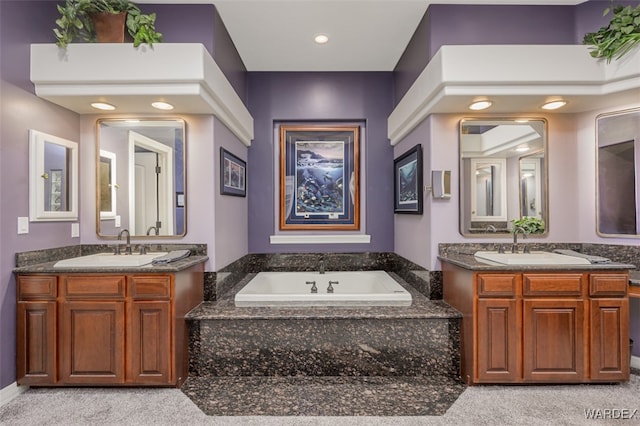 full bath featuring recessed lighting, two vanities, a sink, and a bath