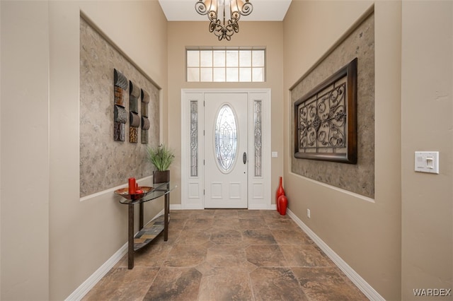 foyer featuring an inviting chandelier, stone finish flooring, and baseboards