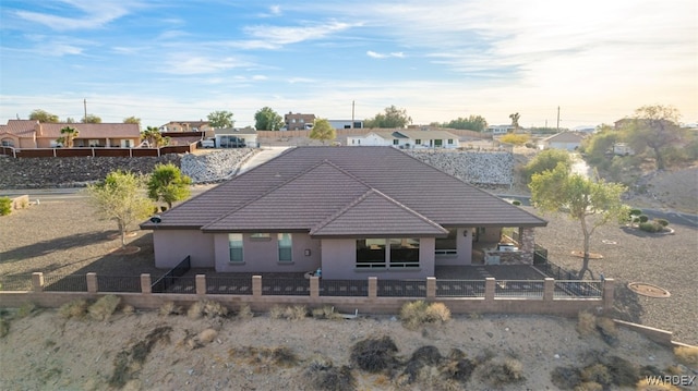 back of property featuring a fenced front yard, a residential view, and a tiled roof