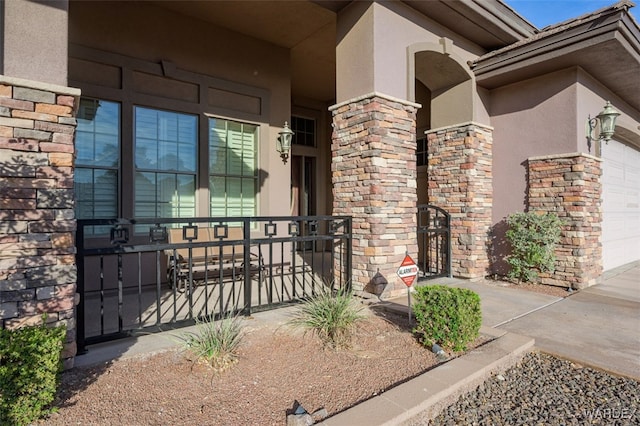 property entrance with a garage, stone siding, and stucco siding