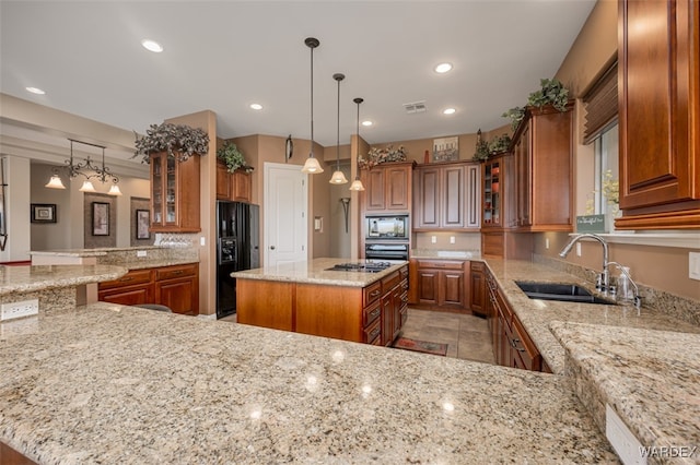 kitchen featuring brown cabinetry, a kitchen island, glass insert cabinets, light stone countertops, and black appliances