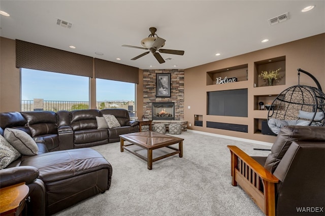 living area featuring light carpet, built in shelves, a fireplace, and visible vents