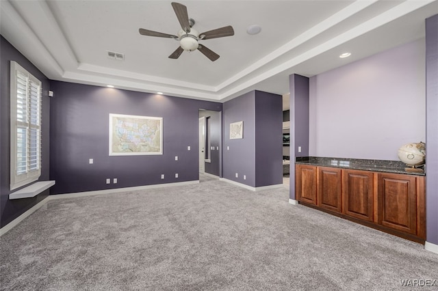 cinema room featuring visible vents, baseboards, a raised ceiling, light colored carpet, and ceiling fan