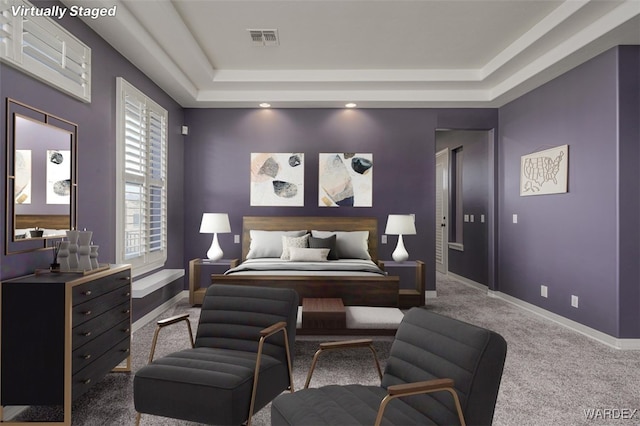 carpeted bedroom with a tray ceiling, visible vents, and baseboards