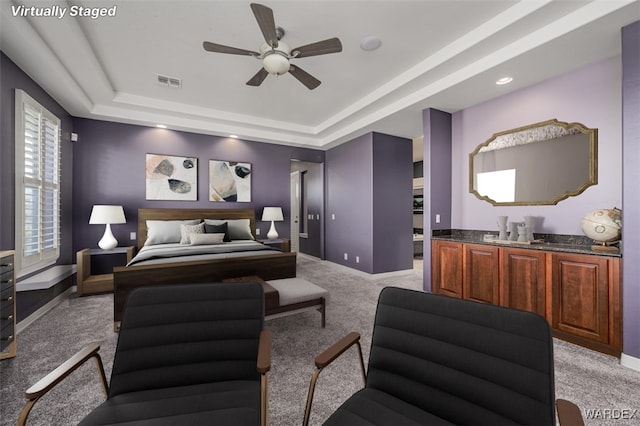 bedroom featuring baseboards, a tray ceiling, visible vents, and light colored carpet