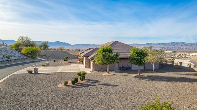 view of front of house with central AC unit, a tile roof, a mountain view, and stucco siding