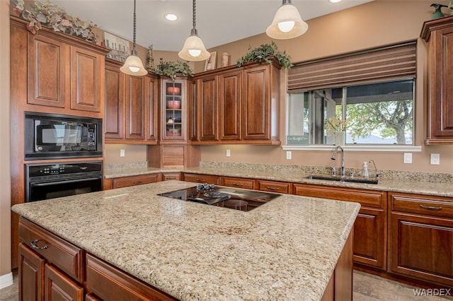 kitchen with black appliances, brown cabinets, a sink, and decorative light fixtures