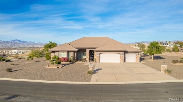 view of front of house featuring an attached garage, stone siding, driveway, and a mountain view