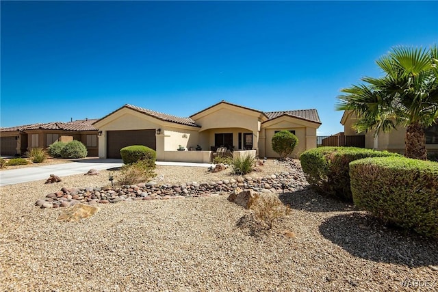 mediterranean / spanish house with driveway, a tiled roof, an attached garage, and stucco siding