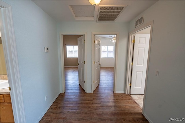 hall featuring wood finished floors, visible vents, and baseboards