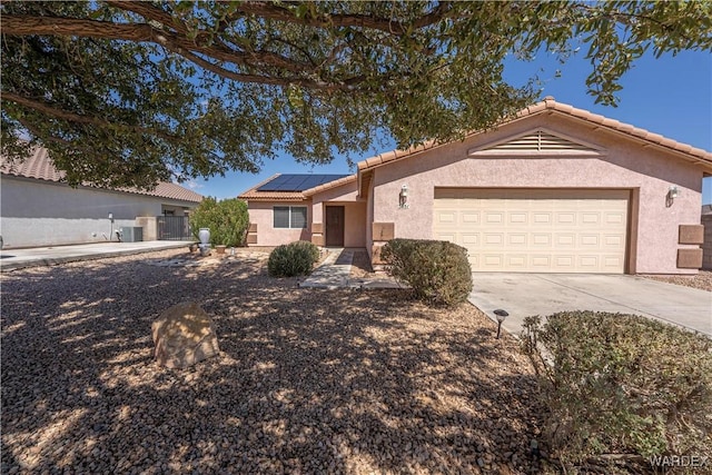 ranch-style house with solar panels, a tiled roof, concrete driveway, stucco siding, and a garage