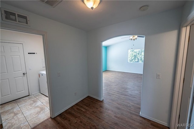 unfurnished room featuring arched walkways, visible vents, baseboards, and wood finished floors