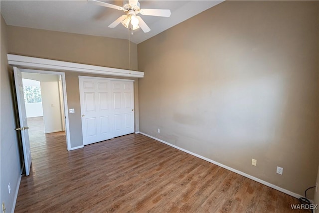 unfurnished bedroom with a closet, lofted ceiling, baseboards, and wood finished floors