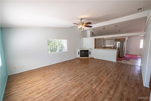 unfurnished living room featuring visible vents, baseboards, lofted ceiling, wood finished floors, and a ceiling fan