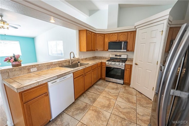 kitchen featuring a peninsula, ceiling fan, a sink, vaulted ceiling, and appliances with stainless steel finishes