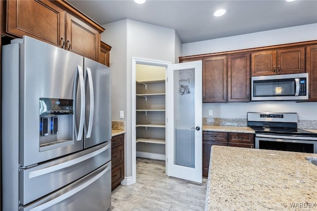 kitchen featuring stainless steel appliances, light wood-style flooring, recessed lighting, and light stone countertops