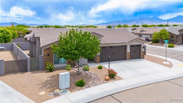 view of front of house with a mountain view, an attached garage, a tile roof, stone siding, and a gate
