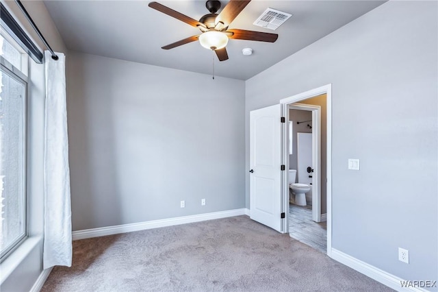 unfurnished bedroom featuring ensuite bathroom, visible vents, ceiling fan, carpet floors, and baseboards