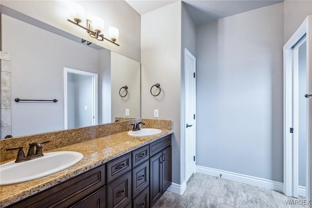bathroom featuring baseboards, double vanity, and a sink
