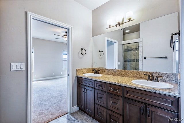 full bath featuring double vanity, a shower stall, ceiling fan, and a sink