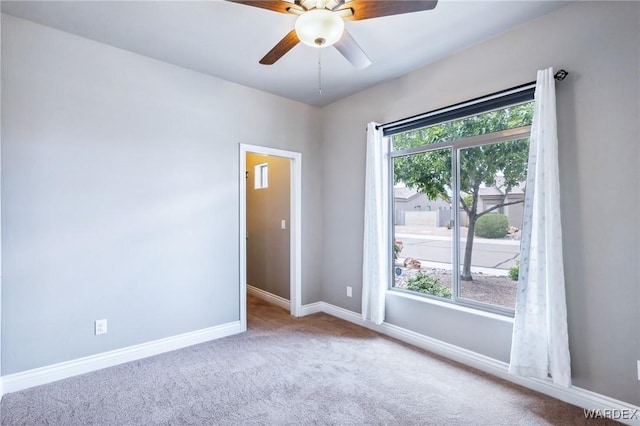 carpeted empty room with baseboards and a ceiling fan