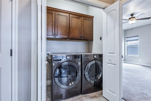 washroom featuring cabinet space, washing machine and clothes dryer, light carpet, a ceiling fan, and baseboards