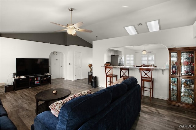 living room with arched walkways, vaulted ceiling, dark wood finished floors, and a ceiling fan