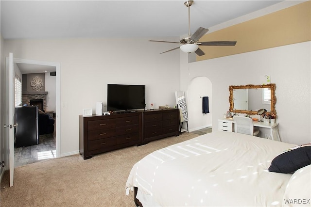 bedroom with a fireplace, light carpet, vaulted ceiling, ceiling fan, and baseboards