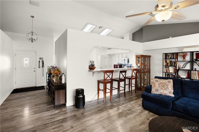 living room with dark wood-style floors, visible vents, vaulted ceiling, and ceiling fan with notable chandelier