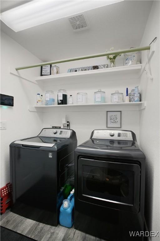 laundry area featuring laundry area, wood finished floors, washing machine and clothes dryer, and visible vents