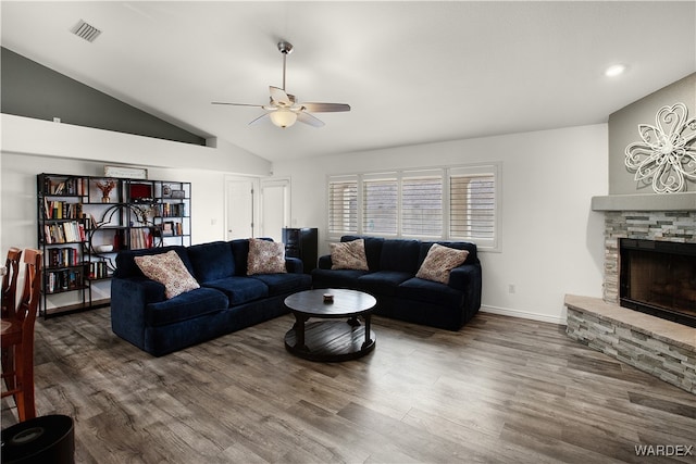 living room with dark wood-style floors, visible vents, ceiling fan, a stone fireplace, and baseboards