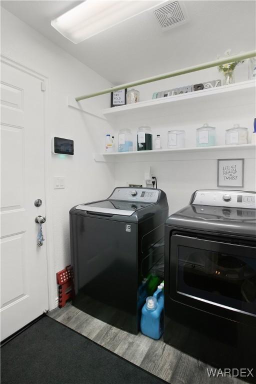 clothes washing area featuring laundry area, visible vents, and washer and clothes dryer