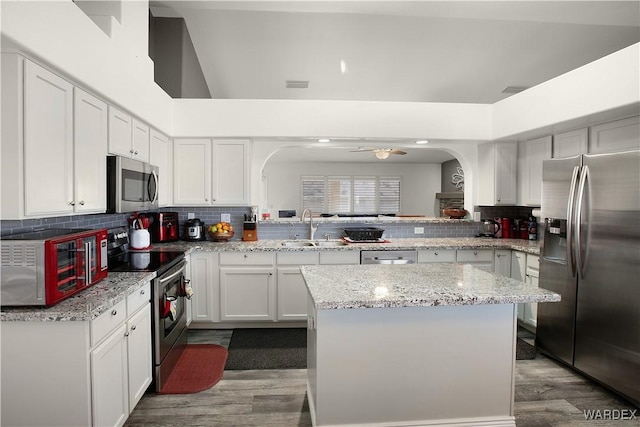 kitchen with appliances with stainless steel finishes, a kitchen island, a sink, and white cabinets