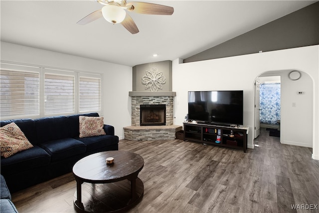 living area featuring lofted ceiling, ceiling fan, a fireplace, wood finished floors, and baseboards