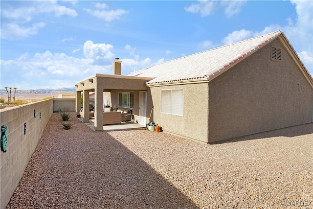 rear view of property featuring a patio, a chimney, a fenced backyard, and stucco siding