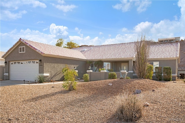 ranch-style home featuring a garage, driveway, a tiled roof, and stucco siding