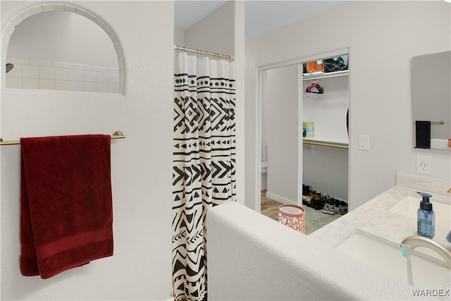 full bathroom with double vanity, curtained shower, a sink, and toilet