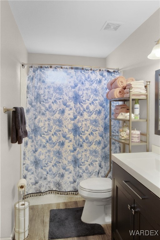 full bathroom with curtained shower, toilet, wood finished floors, vanity, and visible vents